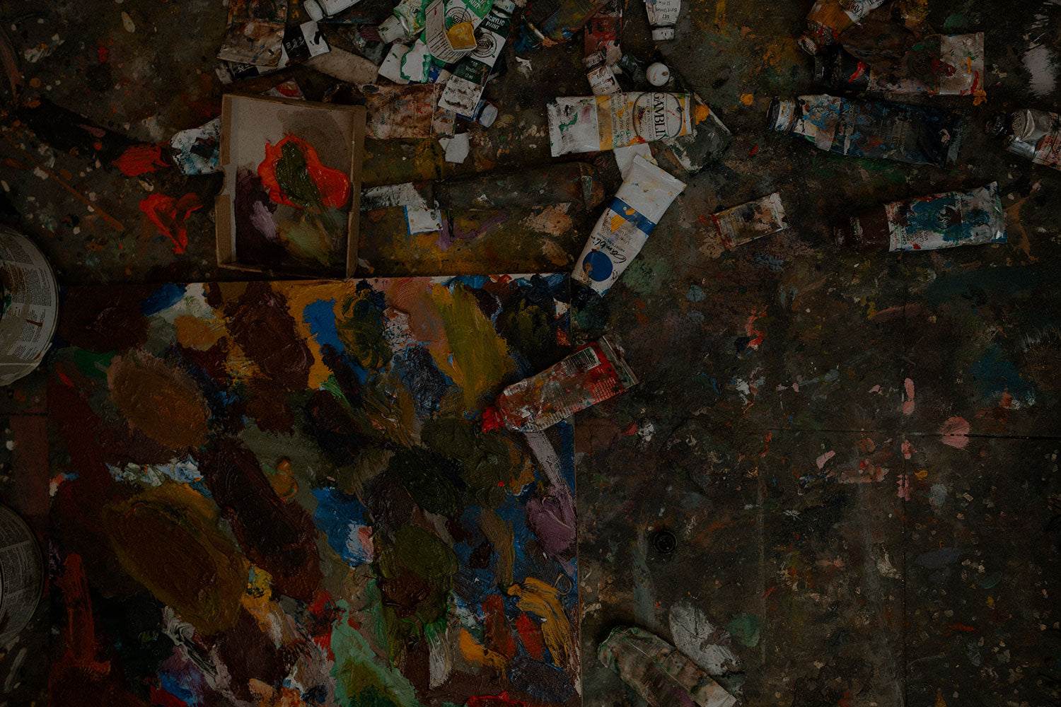 Art supplies including paint tubes and brushes on a dark surface