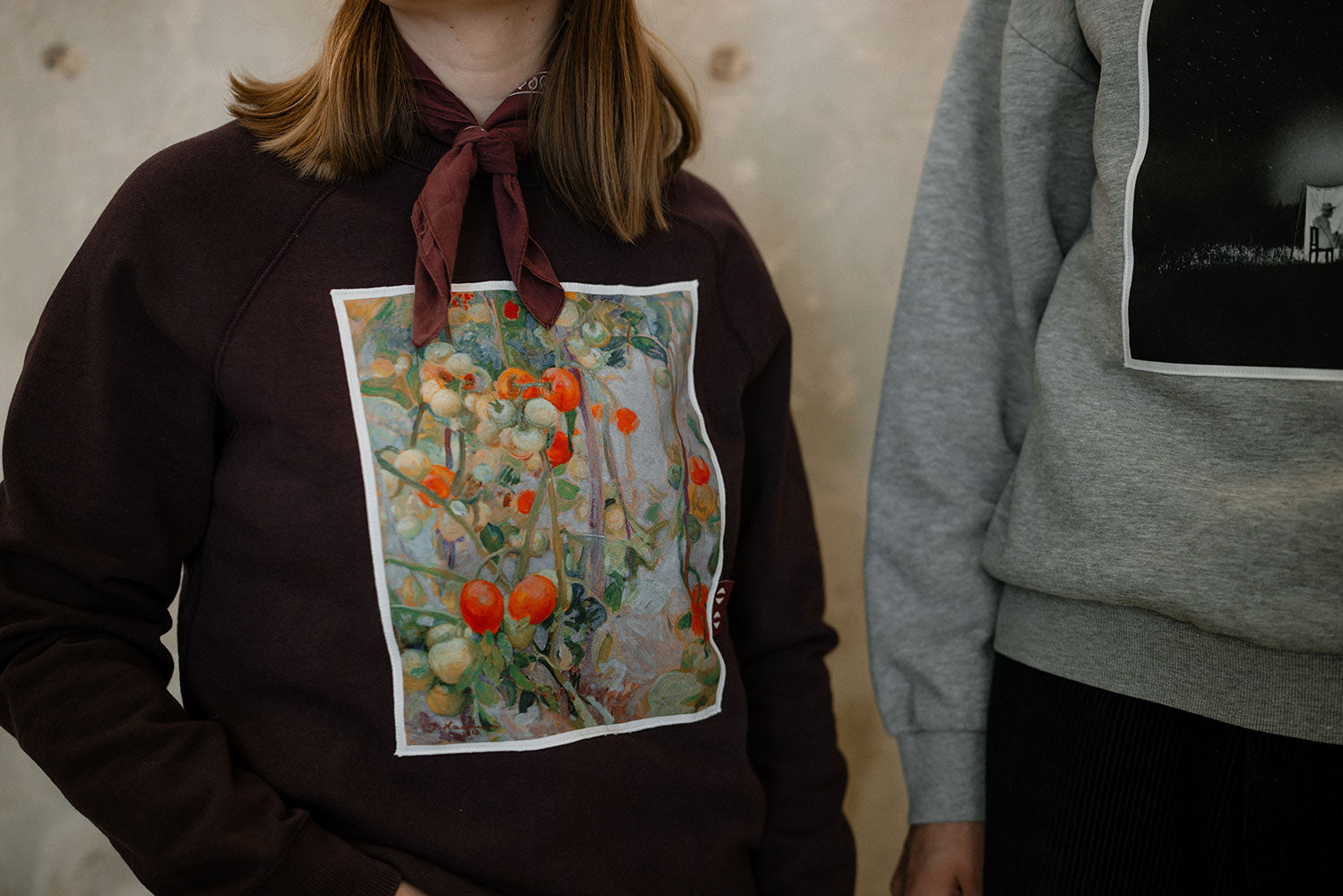 Person wearing a sweatshirt with a colorful graphic design on a neutral background