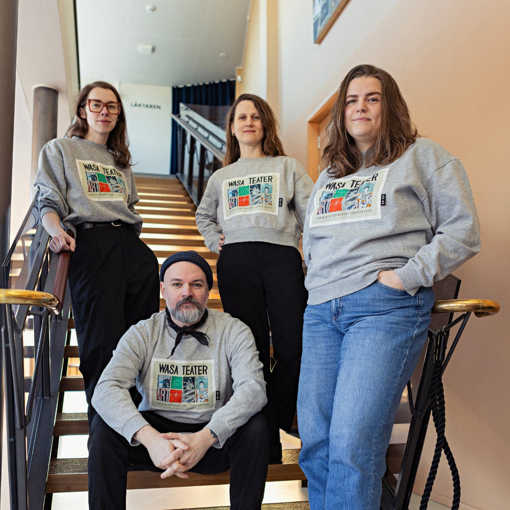 Four people wearing gray sweatshirts with a logo on a staircase.